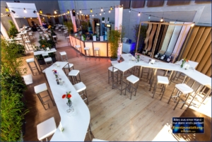 Eventausstattung mit modernen weißen Stehtischen, LED-Bar, Pflanzen und Lichterketten für Firmenfest